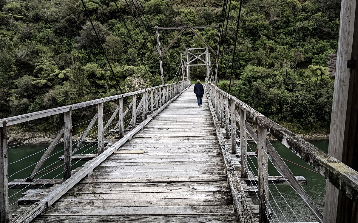 A woman walking over a very old timber bridge