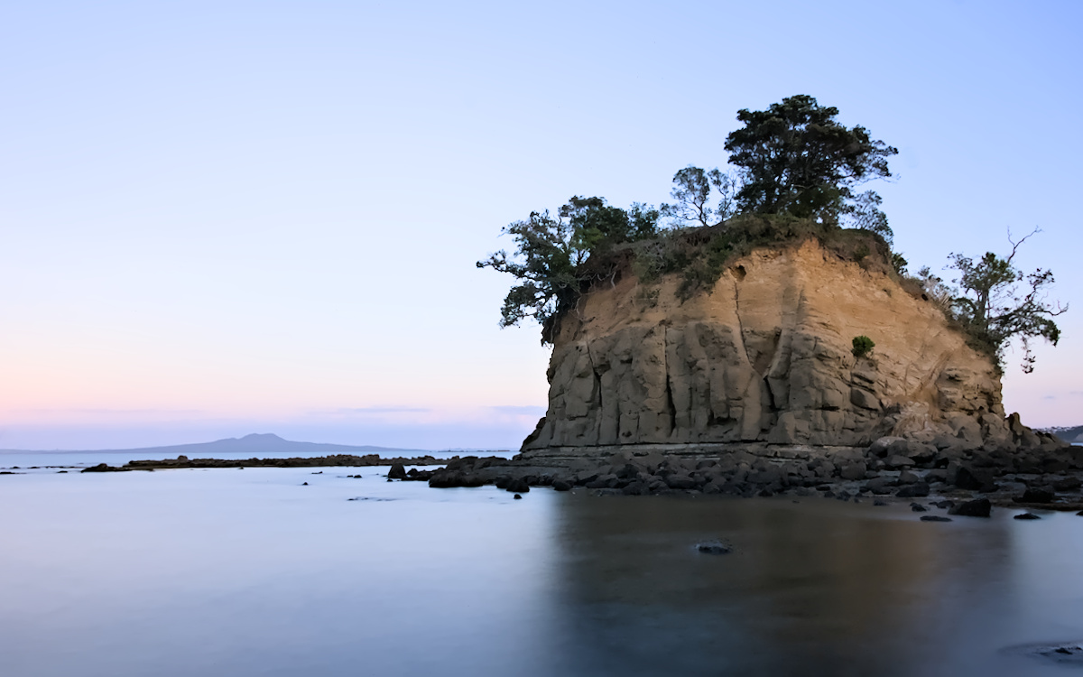 The Tor, a small island, at dusk, at low tide looking towards Rangitoto Island in the distance