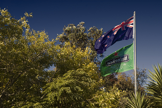 A flag pole with 2 flags, the new Zealand flag and a Heineken flag