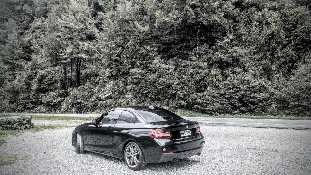A black BMW M235i parked beside the highway